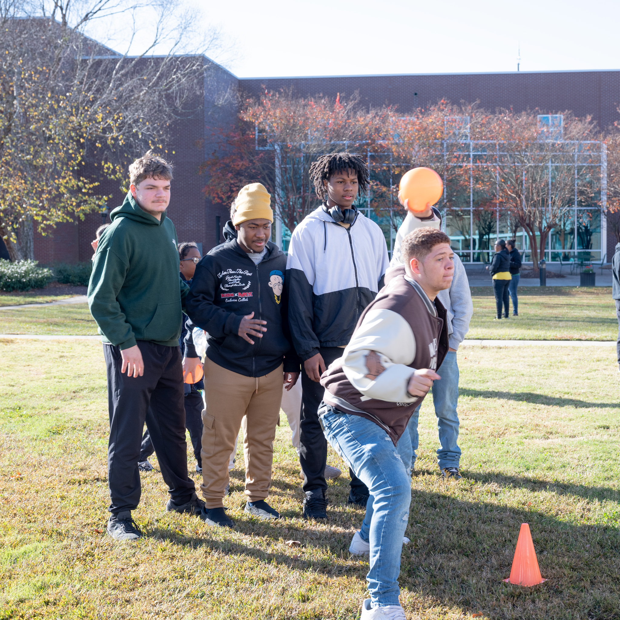 Fall Fest: Student with arm cocked to trow ball at bucket pyramid