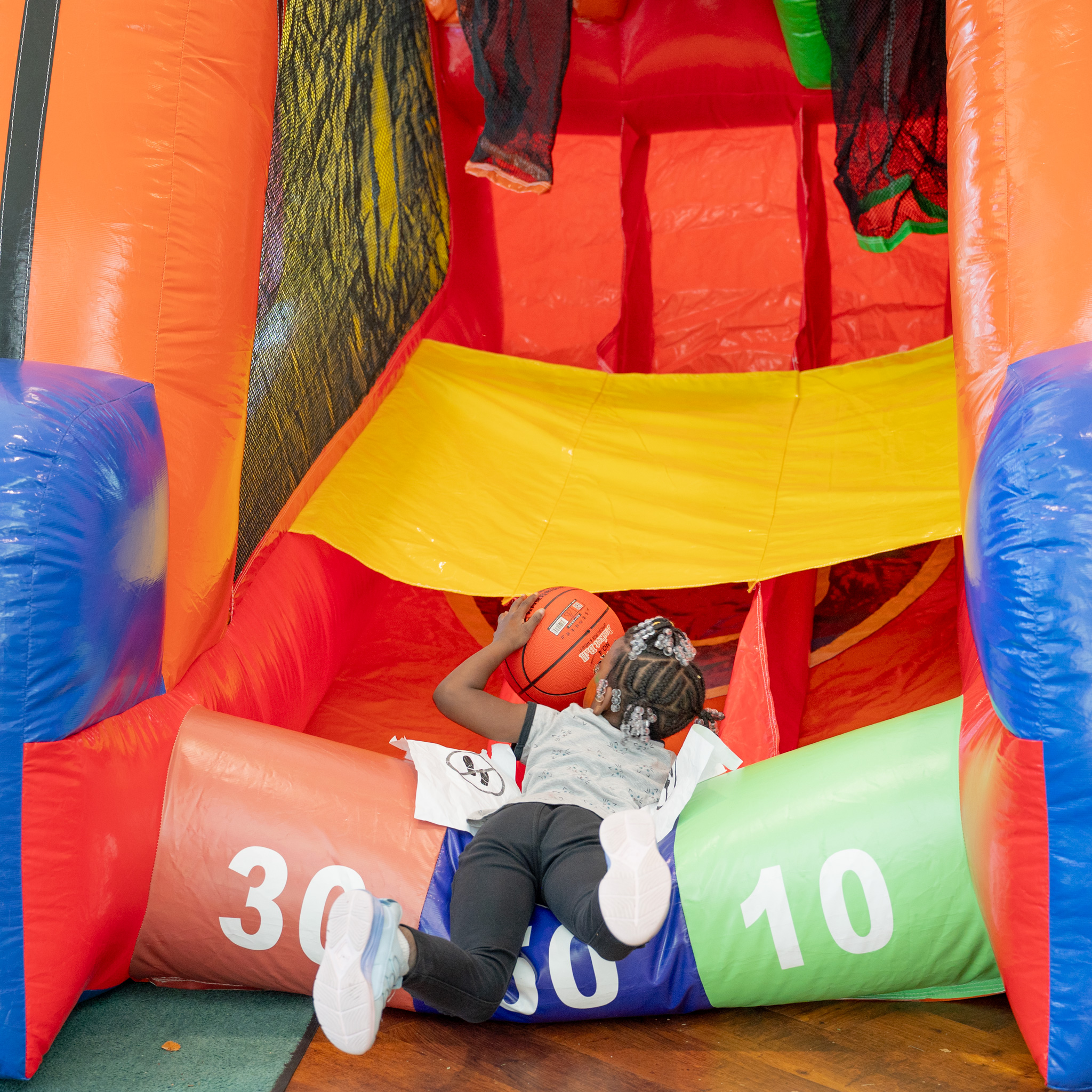 Fall Fest: an Elementary student leans into the inflatable basketball game to get the ball