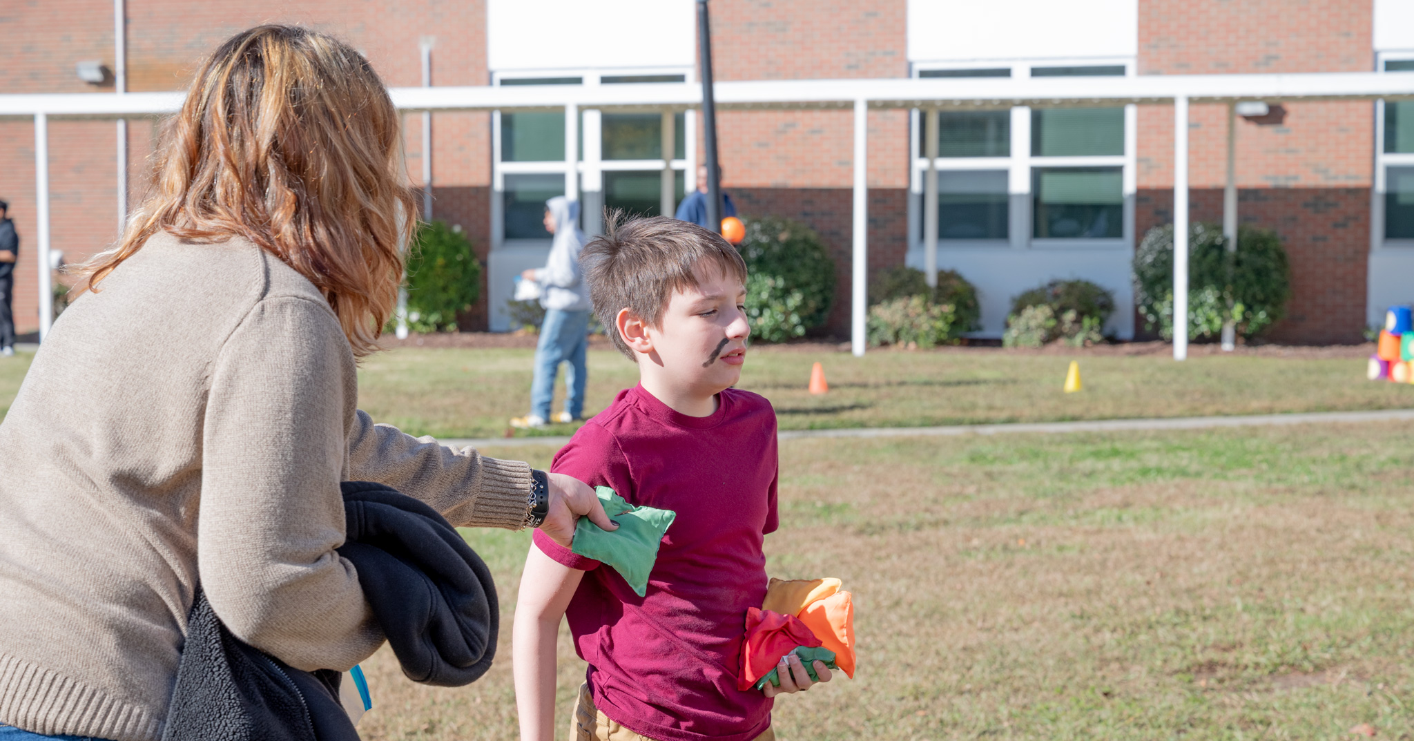 Fall Fest: A mother gives her son bean bags to throw for the corn hole game