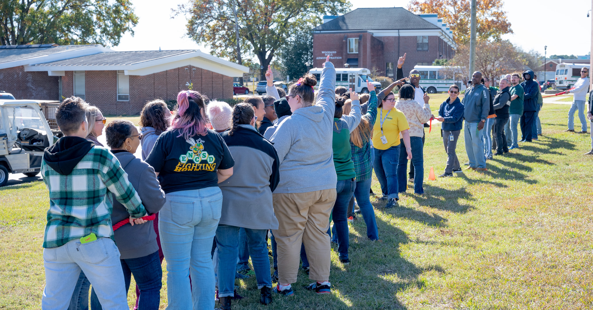 Fall Fest: Women staff members making 'ready' signs while the men strategize