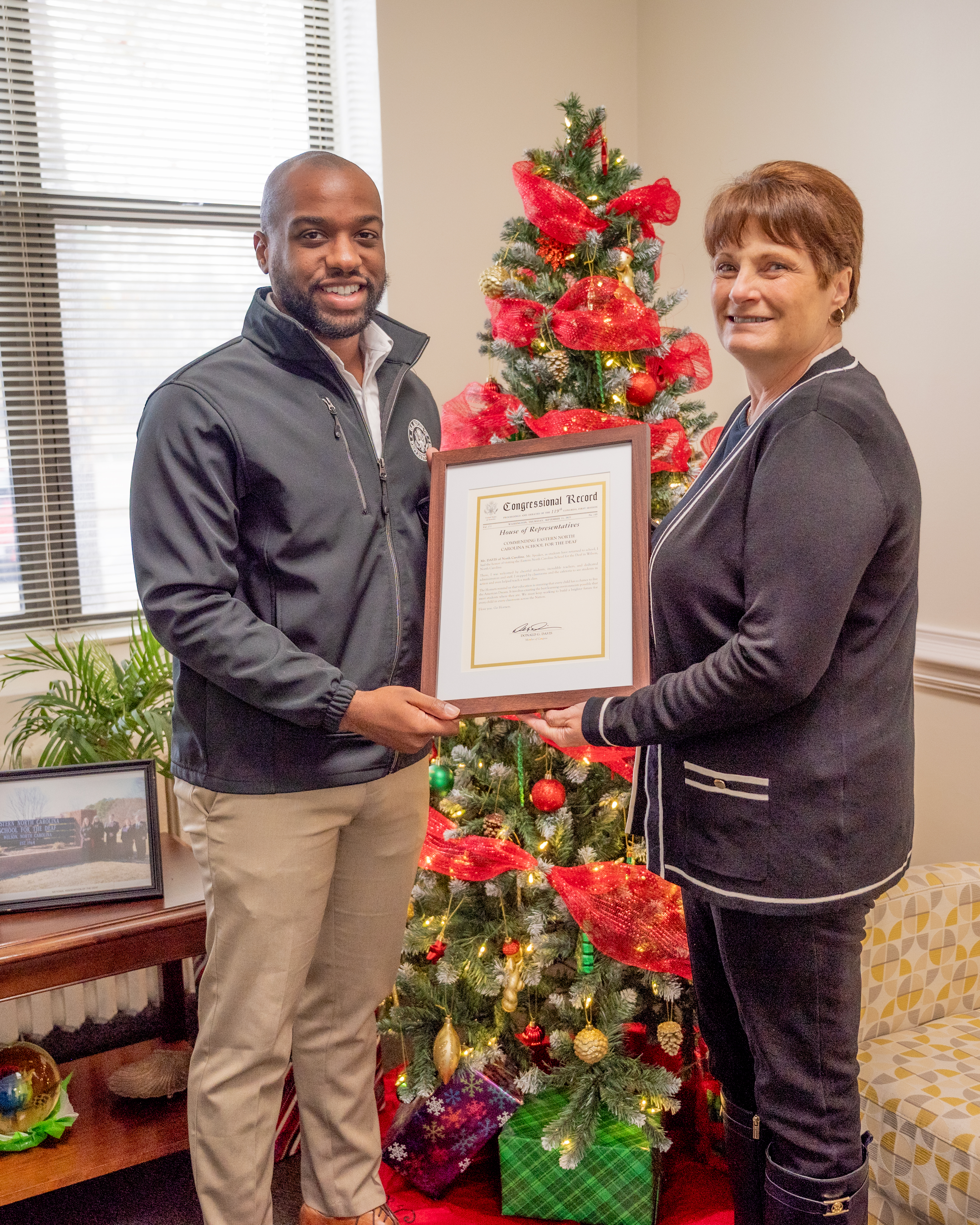 Cheryl Iannucci receives a congressional record from a representative of Congressman Don Davis's office.
