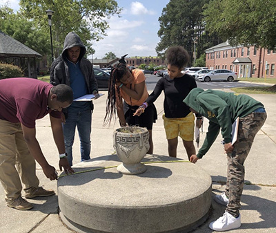 Students measuring the dimensions of a concrete barrier.