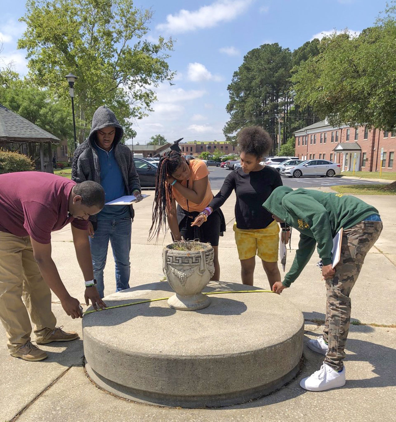 Students measuring the dimensions of a concrete barrier.